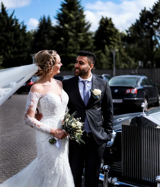 A bride and groom are captured in a moment of happiness during their wedding celebration. The bride is wearing an elegant white lace wedding gown with long sleeves and an off-the-shoulder neckline, ho